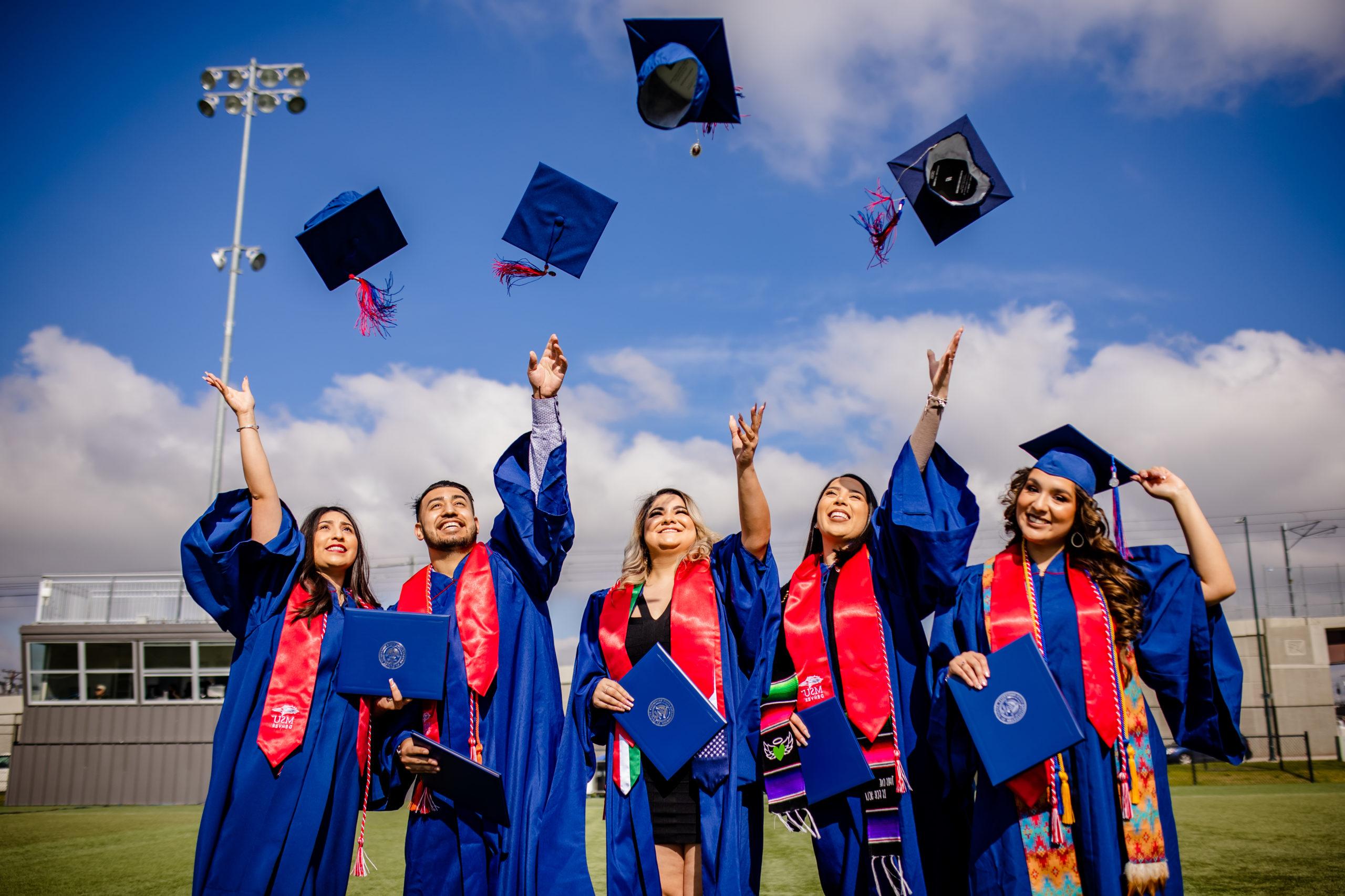 密歇根州立大学丹佛 students celebrating graduating by throwing their graduation caps in the air