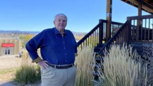 Jerry Hilderbrand standing at the bottom of stairs with mountains and fall colors in the background